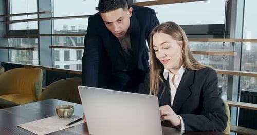 Portrait of a Man and a Woman Discussing Work with Notebook in the Brightly Lit Modern Office