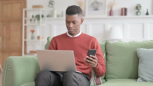 Man Using Laptop and Smartphone at Home