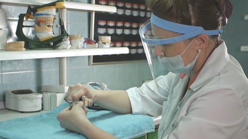 Dental Technician Working Meticulously on Dental Mold in Lab