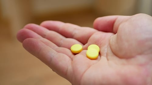 Person gießt ein paar verschreibungspflichtige gelbe Opiatpillen in die Hand