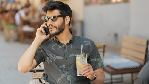 Young Adult Talking on Smartphone at Outdoor Cafe