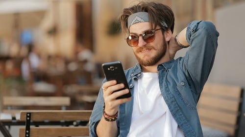 Smiling Man Using Smartphone at Outdoor Cafe