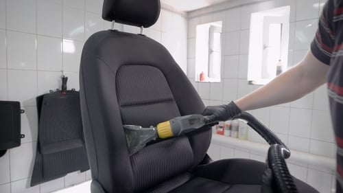 Man Vacuuming Removed Car Seat in Carwash.