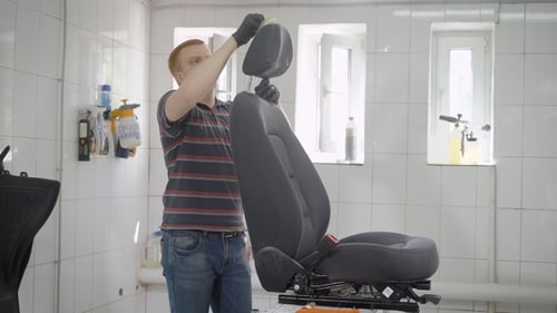 Professional Worker Cleaning Car Seat in Carwash.
