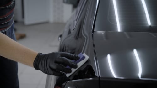 Detailer Applying Product to Glossy Black Car