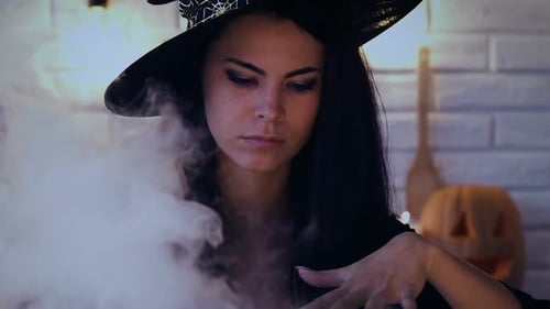 Young Woman Dressed as Witch Stirring Cauldron