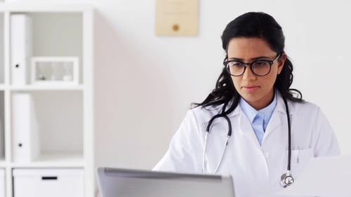 Female Doctor with Laptop and Papers at Hospital