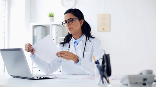 Female Doctor with Laptop and Papers at Hospital
