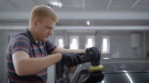 Young Adult Polishing Black Car in a Garage
