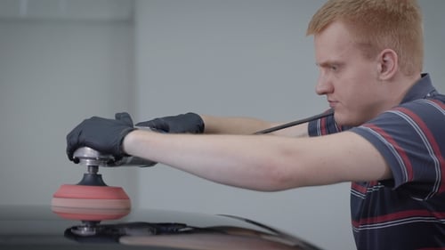 Man Polishing Black Car with Electric Buffer