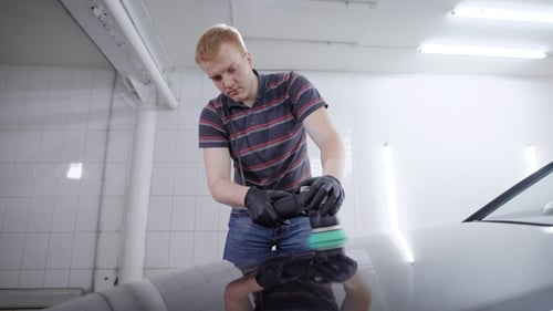 Professional Polishing Black Car Hood with Special Polishing Machine on a Car Service.