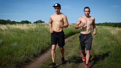Men Running Shirtless Through Grassy Rural Field