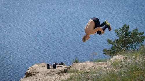 Muscular Man Doing a Backflip in on the Hill in Summer.