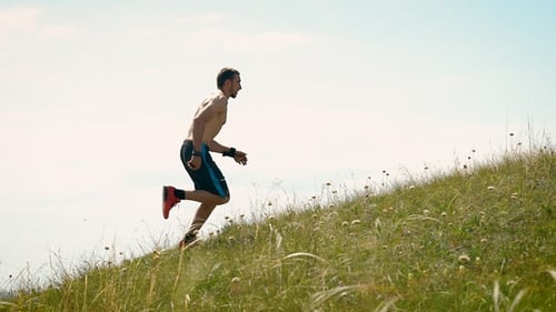 Side View Shot of a Strong Athletic Man Running Up the Hill.
