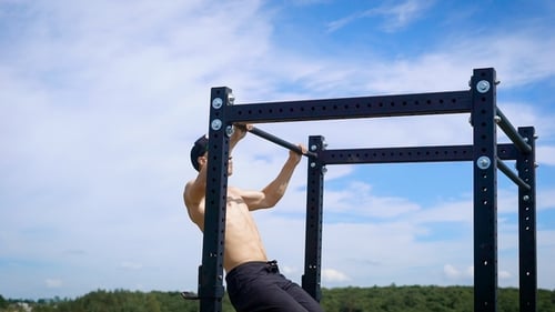 Muscular Shirtless Man Doing Pull Ups on a Bar in Mountains.