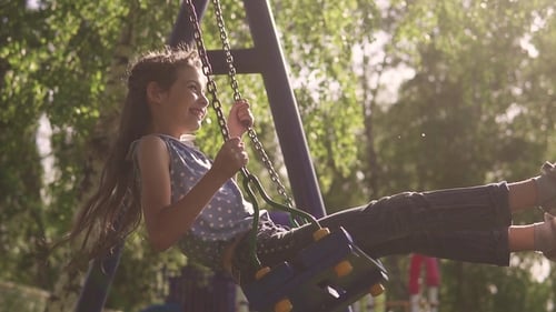 Concept of a Happy and Carefree Childhood. Child Swings on a Swing and Laughs Enthusiastically