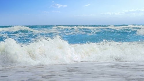 Waves Crashing on Beach Under Blue Sky