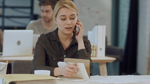 Blonde Woman Talking on Phone, Writing in Office