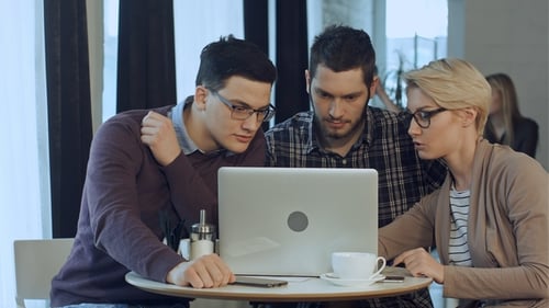 Young Adults Collaborating on Laptop in Modern Cafe