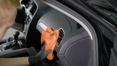 Man Cleaning Vehicle Interior with Orange Cloth