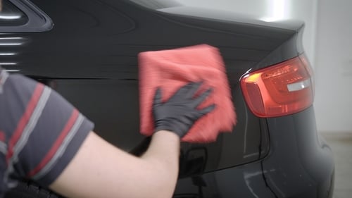 Master Is Polishing a Rear Part of Automobile By Red Soft Cloth in Auto Workshop After Washing