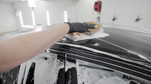 Car Detailer Washing Vehicle with Sponge and Soap