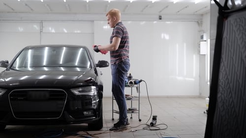 Master Is Rubbing Black Luxury Automobile in a Workshop After Car Washing, Polishing and Giving