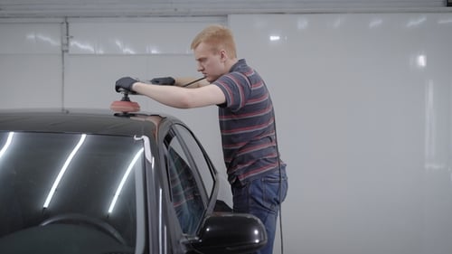 Man Polishing Black Car in Garage
