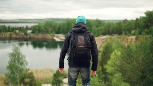 Portrait of Active Young Man Traveller with Knapsack Walking Down the Mountain