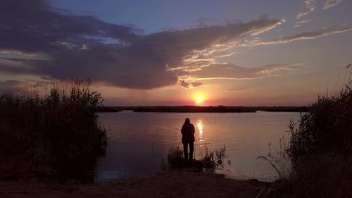 Lone Fisherman in a Quiet Lake at Sunset