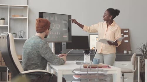 Woman Discussing Marketing Strategy with Colleague in Office