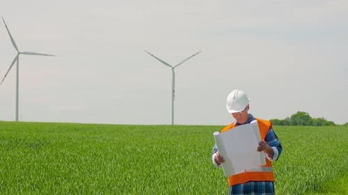 Engineer Analyzing Plan While Looking At Windmill Farm. Eco Energy Concept