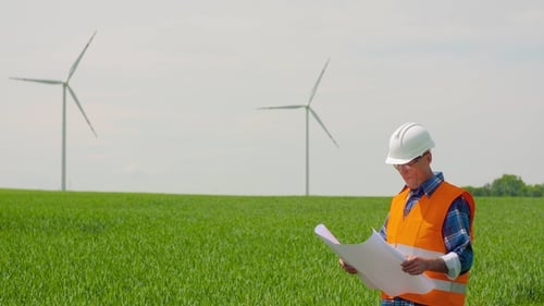 Engineer Analyzing Plan While Looking At Windmill Farm. Eco Energy Concept