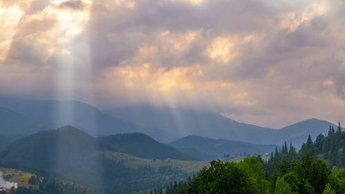 Les rayons du soleil traversent les nuages au-dessus des montagnes au coucher du soleil