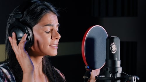 Young Beautiful Brunette Woman Recording Voice, Song or Album in Professional Studio. Girl Sings