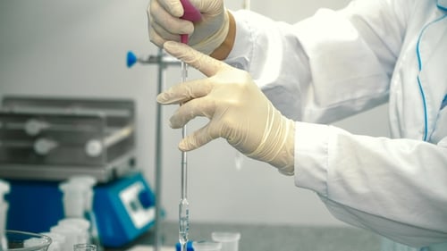Scientist Dispensing Liquid into Laboratory Beakers