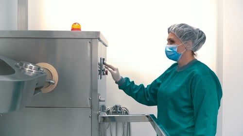 Laborant justiert pharmazeutische Maschine zum Mischen von Pulver und Granulat