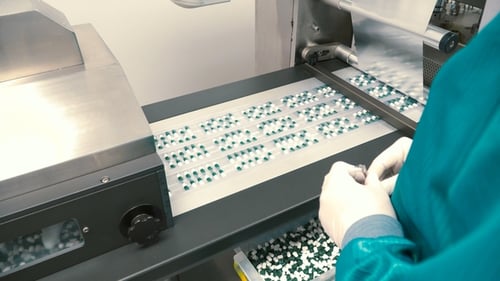 Arbeiter kontrollieren den Prozess des Sortierens von Kapseln in Verpackungen