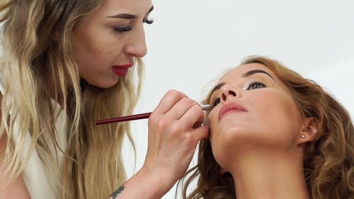 Blonde Makeup Artist Applying Makeup to Woman