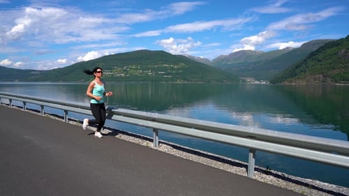 Woman Runs Next to Mountain Lake on Sunny Day