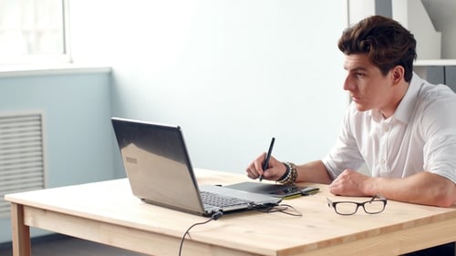 Casual Male Designer Using Graphics Tablet in a Bright Office