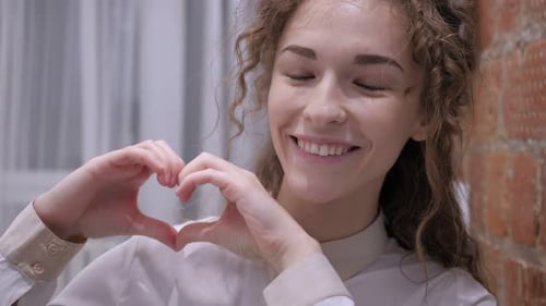 Young Woman Makes Heart Shape with Hands