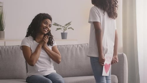 Girl Presents Handmade Card to Smiling Mother