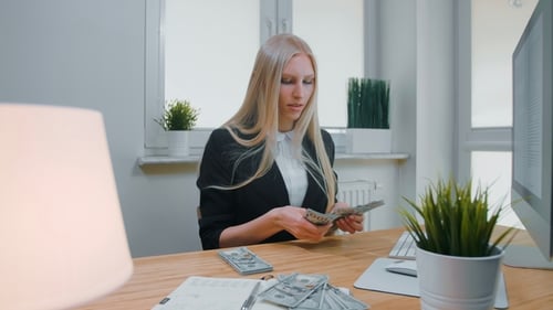 Female Counting Money at Office Workplace. Beautiful Young Blond Woman in Business Suit Sitting in