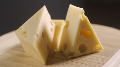 Three Cheese Triangles on a Wooden Cutting Board