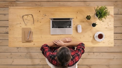 Young woman at office desk looking on monitor laptop