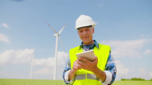 Engineer Using Digital Tablet on Wind Turbine Farm