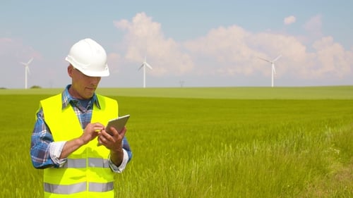 Engineer Using Digital Tablet on Wind Turbine Farm