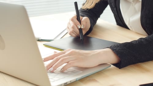 Woman Designs Using Tablet and Computer at Desk