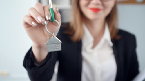 Smiling Young Woman Realtor Hands Over the Keys To New Real Estate